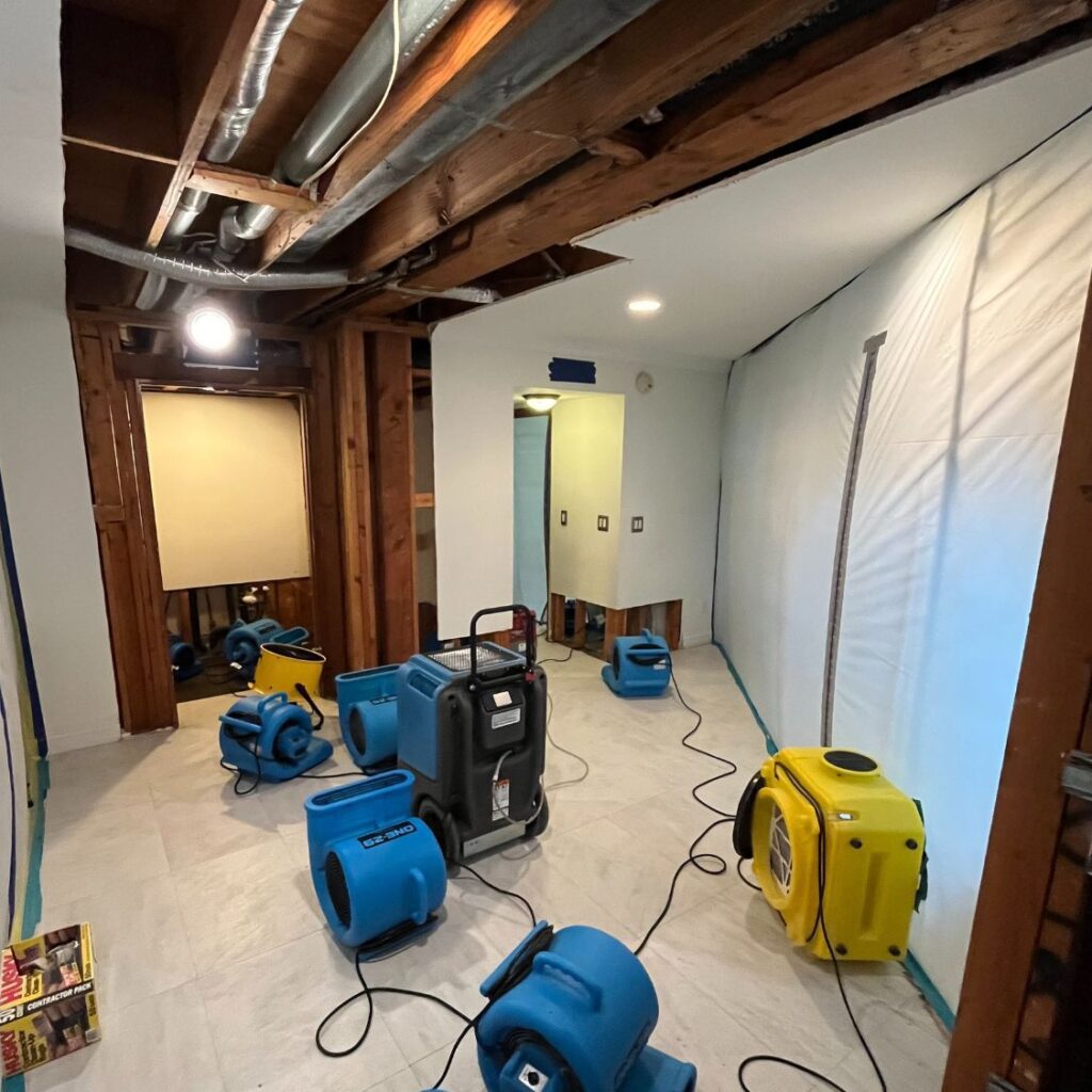 Multiple industrial fans drying a room.